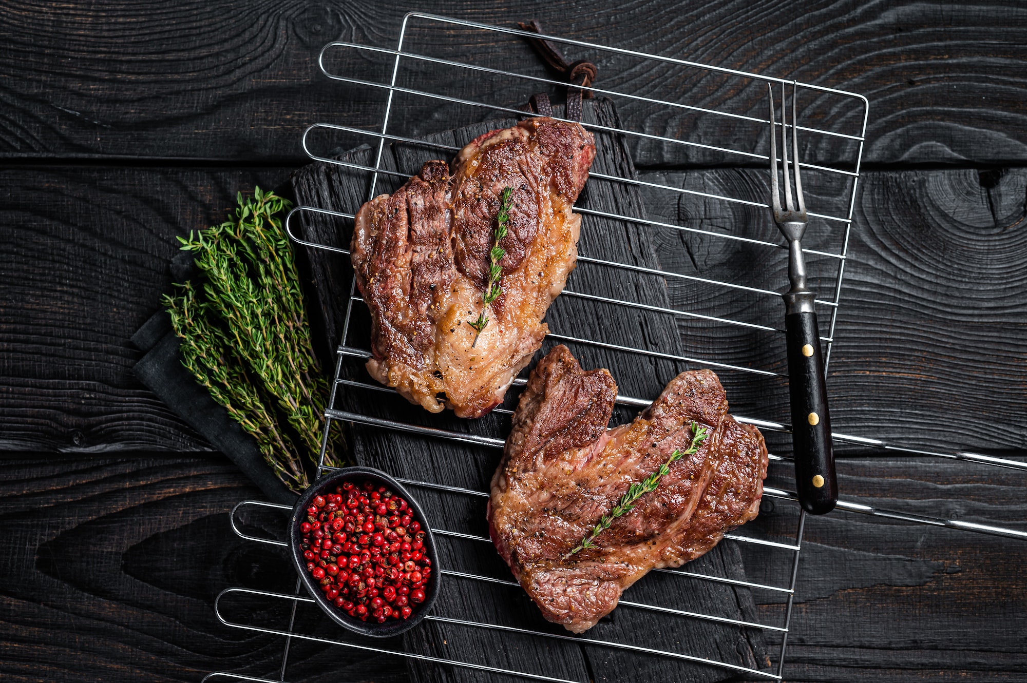 bbq-grilled-chuck-eye-roll-beef-steaks-on-grill-black-wooden-background-top-view.jpg