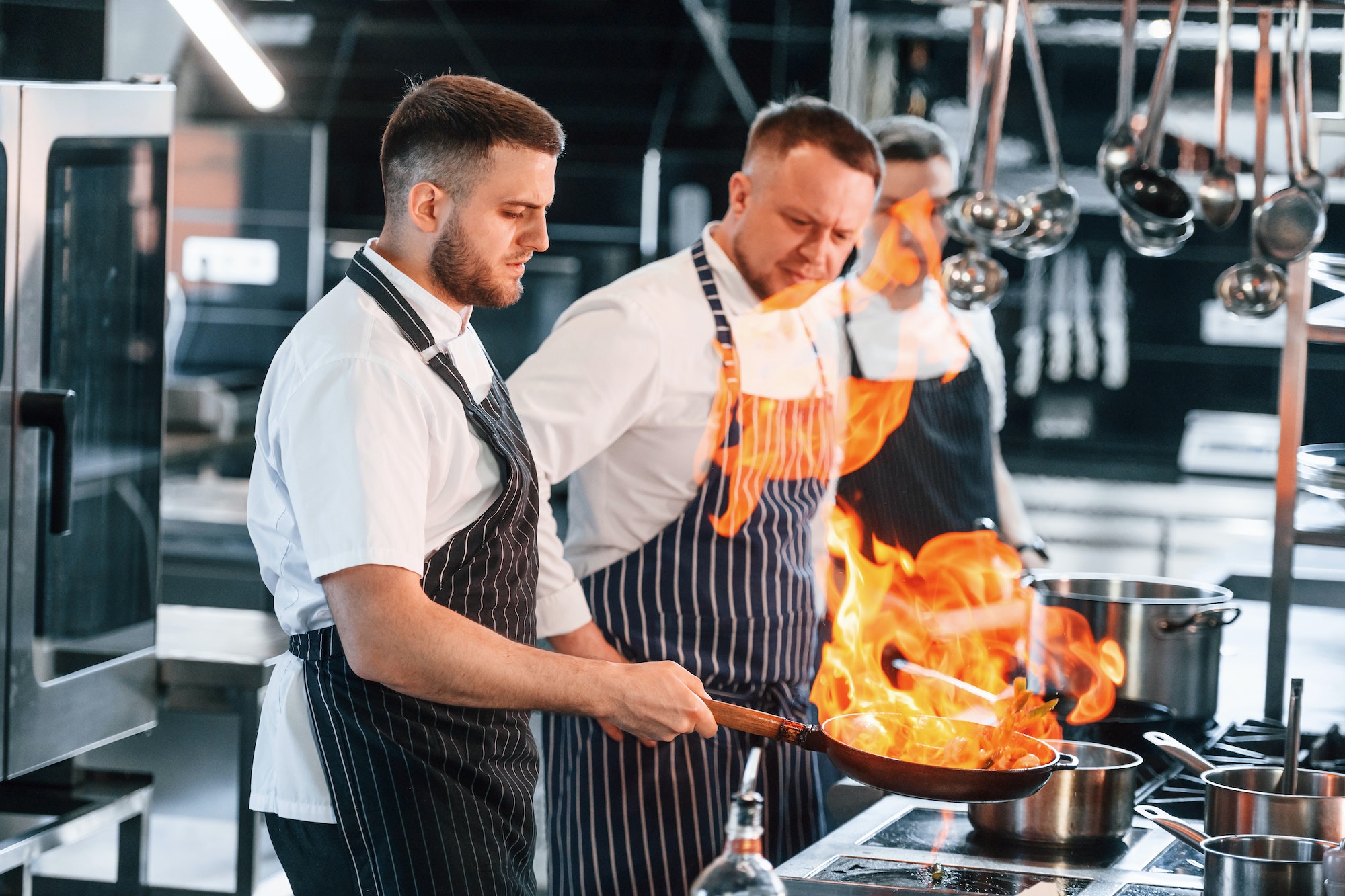 flaming-the-meal-on-frying-pan-kitchen-workers-is-together-preparing-the-food.jpg